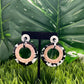 White circle post earrings with larger blush, black and white circles dangling from the post.