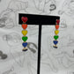 Post earrings with 6 hearts dangling in a line each one a color of the rainbow.