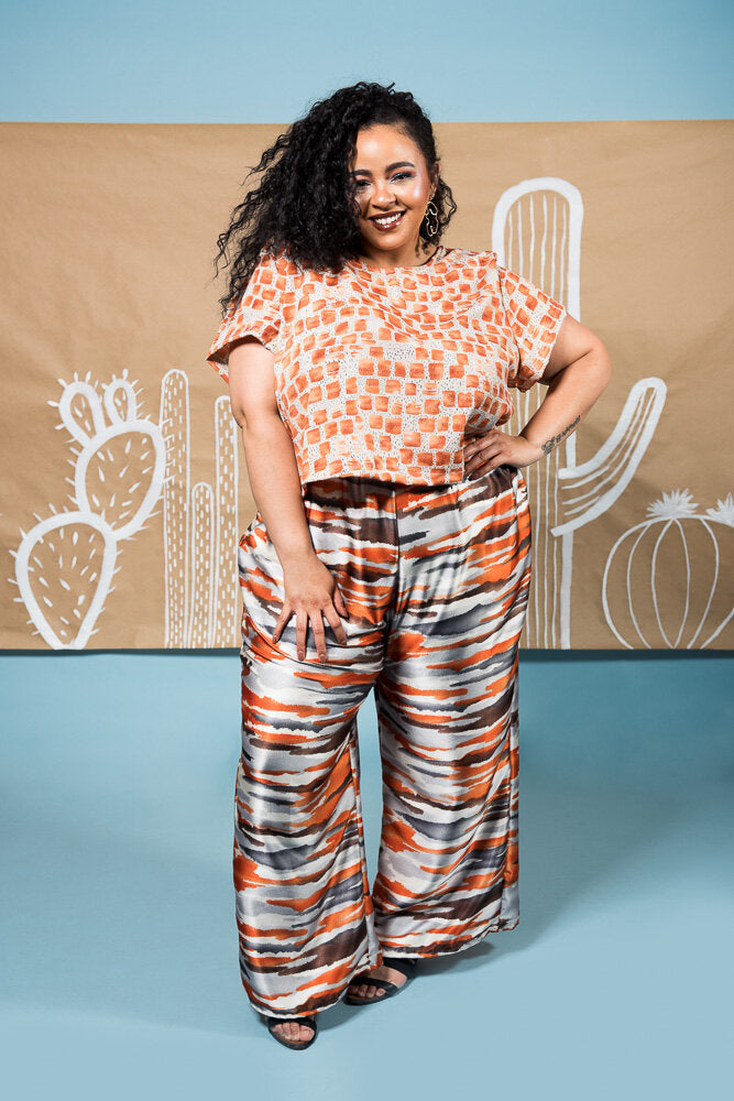 Full length wide leg pant with elastic waist in shiny orange, grey, and white modeled strips