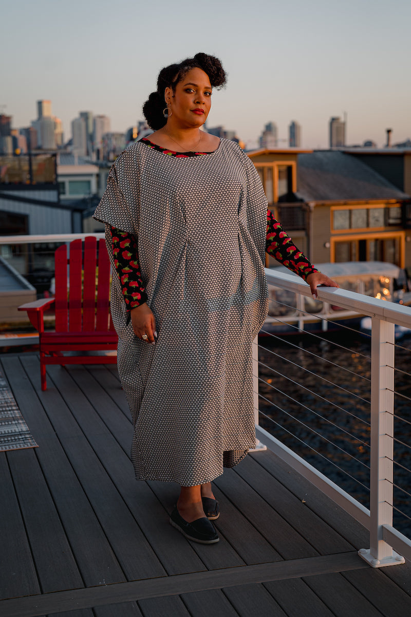 Ankle length dress with black and white Dimond patten. Dress has fish eye darts in the center creating pleats down the skirt. Sleeves are short and drop off the shoulder with pleases at the shoulder.