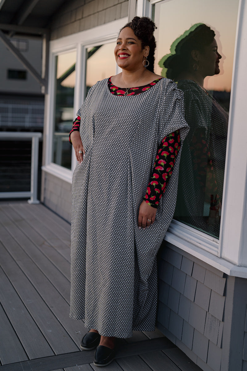 Ankle length dress with black and white Dimond patten. Dress has fish eye darts in the center creating pleats down the skirt. Sleeves are short and drop off the shoulder with pleases at the shoulder.