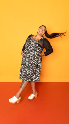 Black knee length overall dress with white vampire teeth print all over.