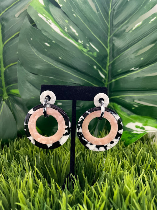 White circle post earrings with larger blush, black and white circles dangling from the post.