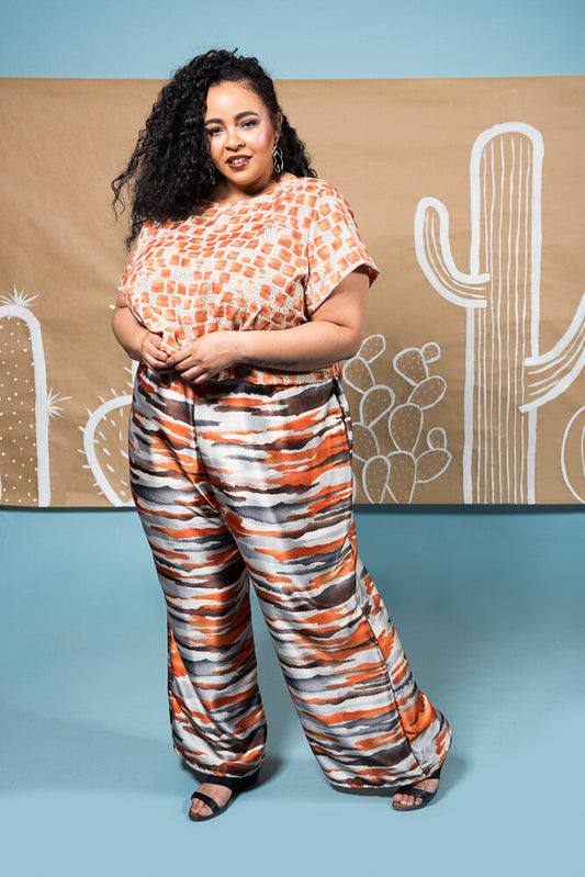Full length wide leg pant with elastic waist in shiny orange, grey, and white modeled strips