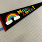 Black pennant flag with a rainbow that says "More Love!" in rainbow letters.