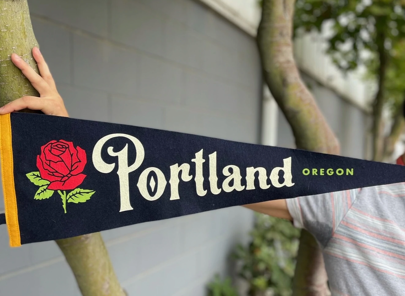 Navy blue pennant flag with a red rose that says "Portland" white in scrawled font and "Oregon" in small green letters.