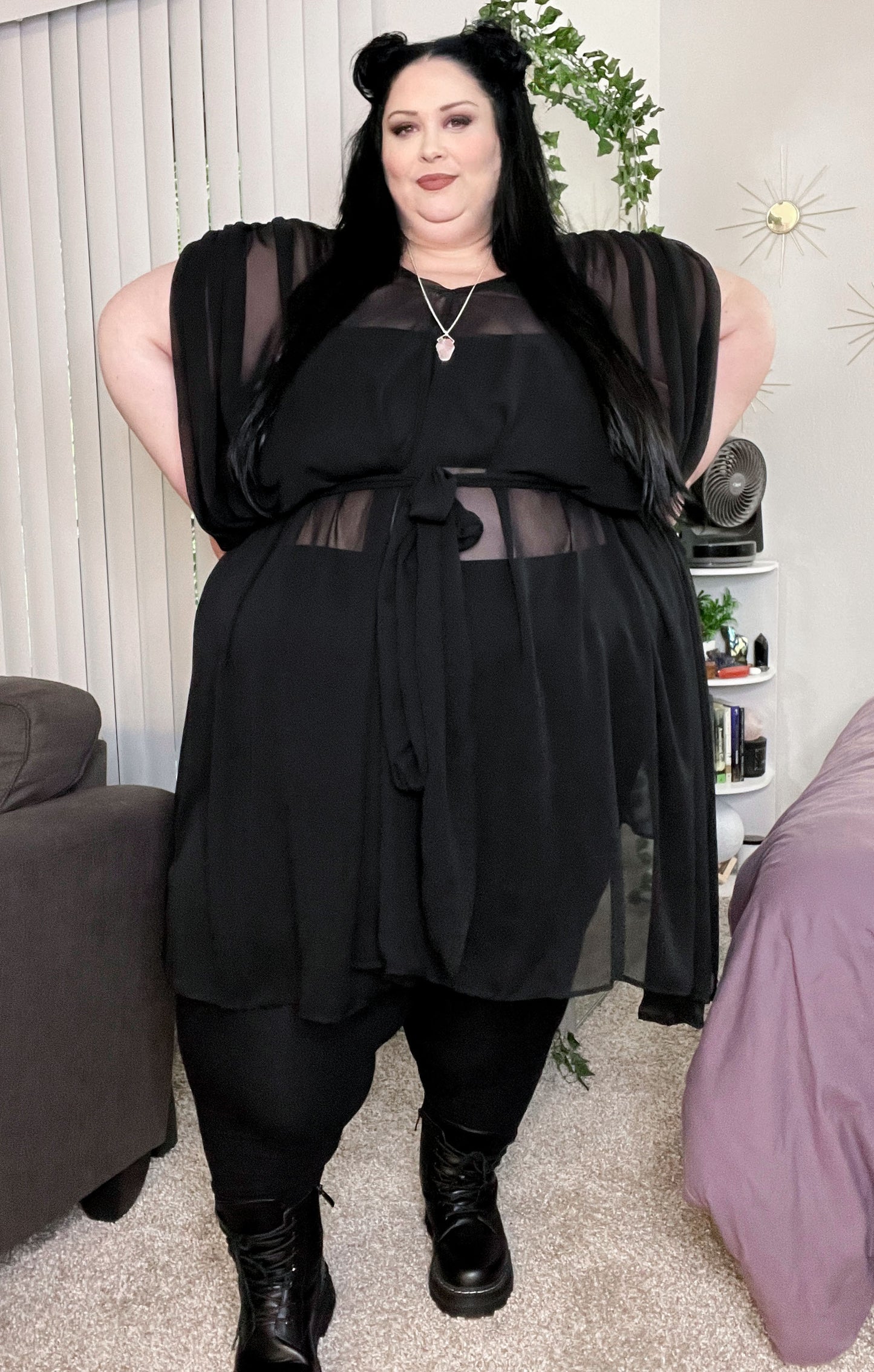 Sheer black flowy midi dress with tie around the middle. Shoulders are pleated and drape down as a sort of waterfall sleeve. 